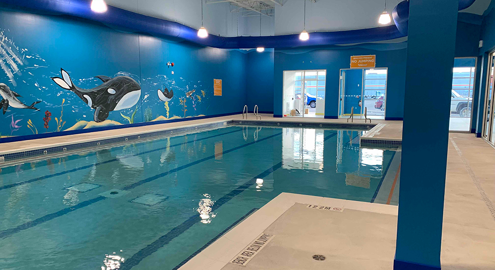 Indoor teaching pool with paintings of whales and fish on the wall at the Goldfish Swim School in Burlington Ontario